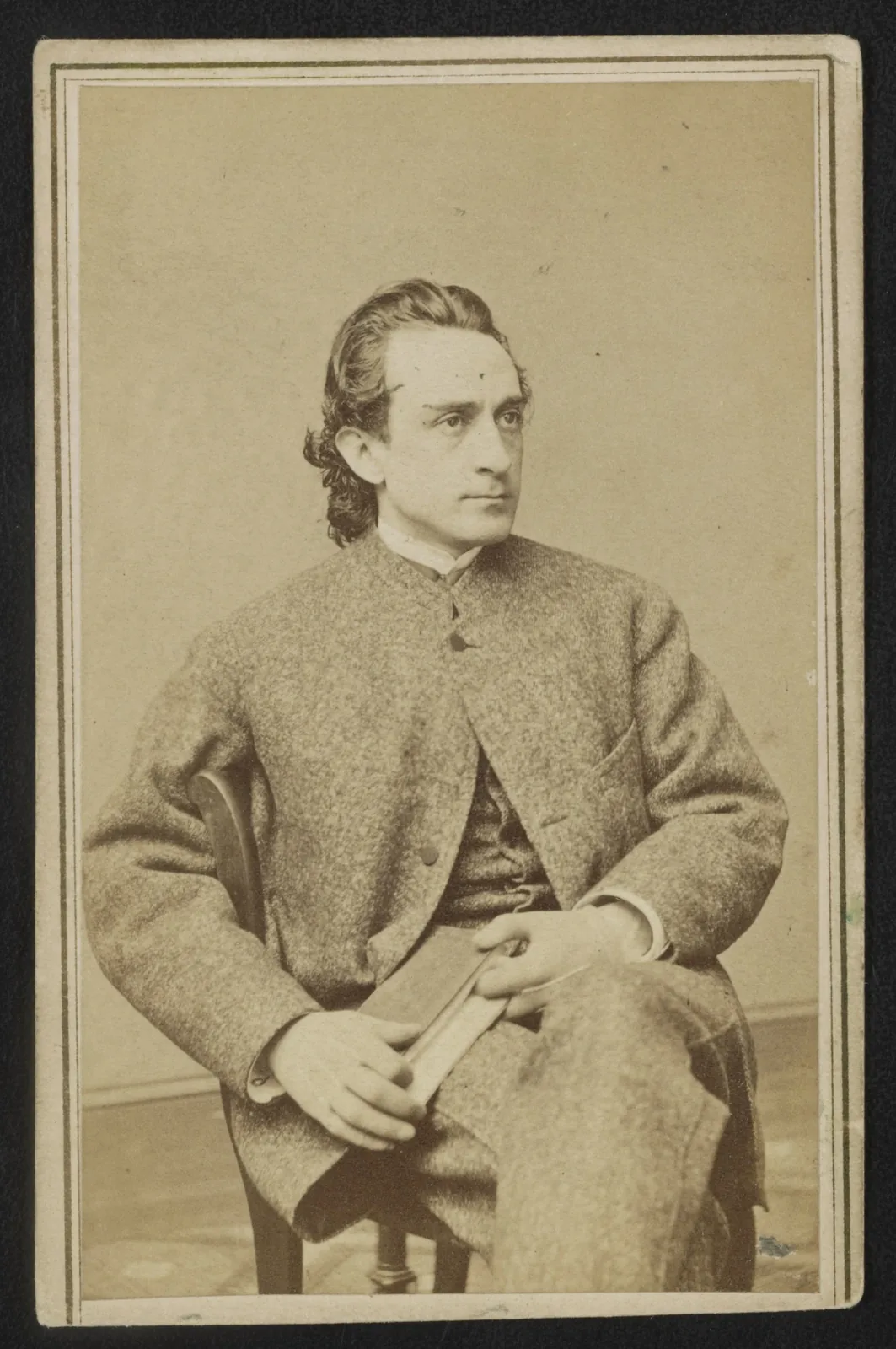 Edwin Booth seated in a suit, looking to the side, about 1865.