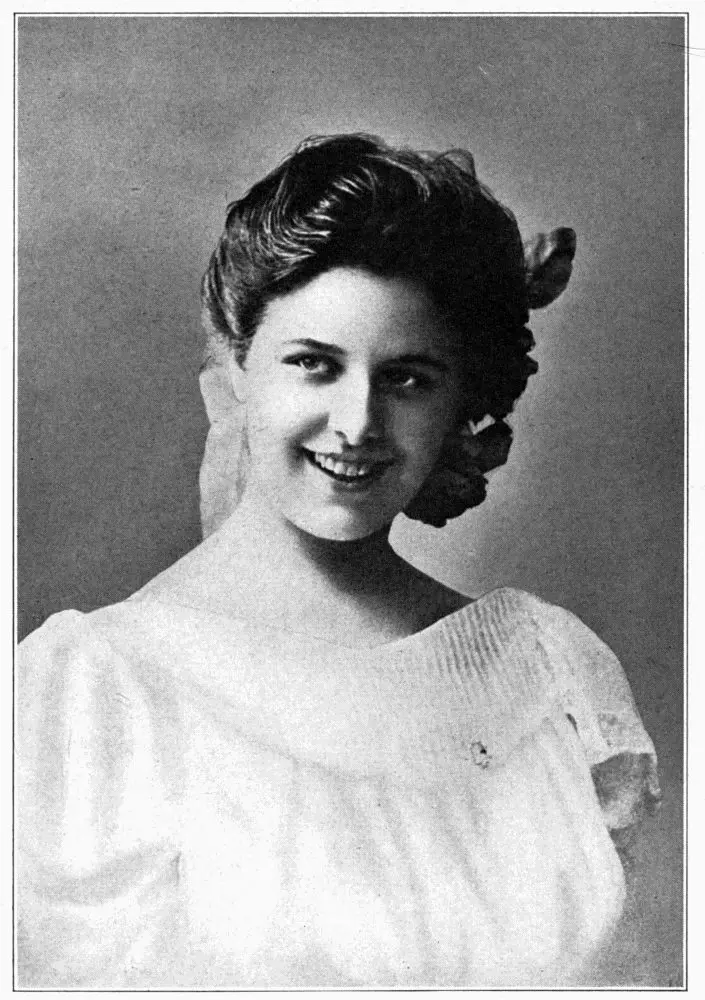 Youthful studio portrait of soprano Geraldine Farrar in a white dress.
