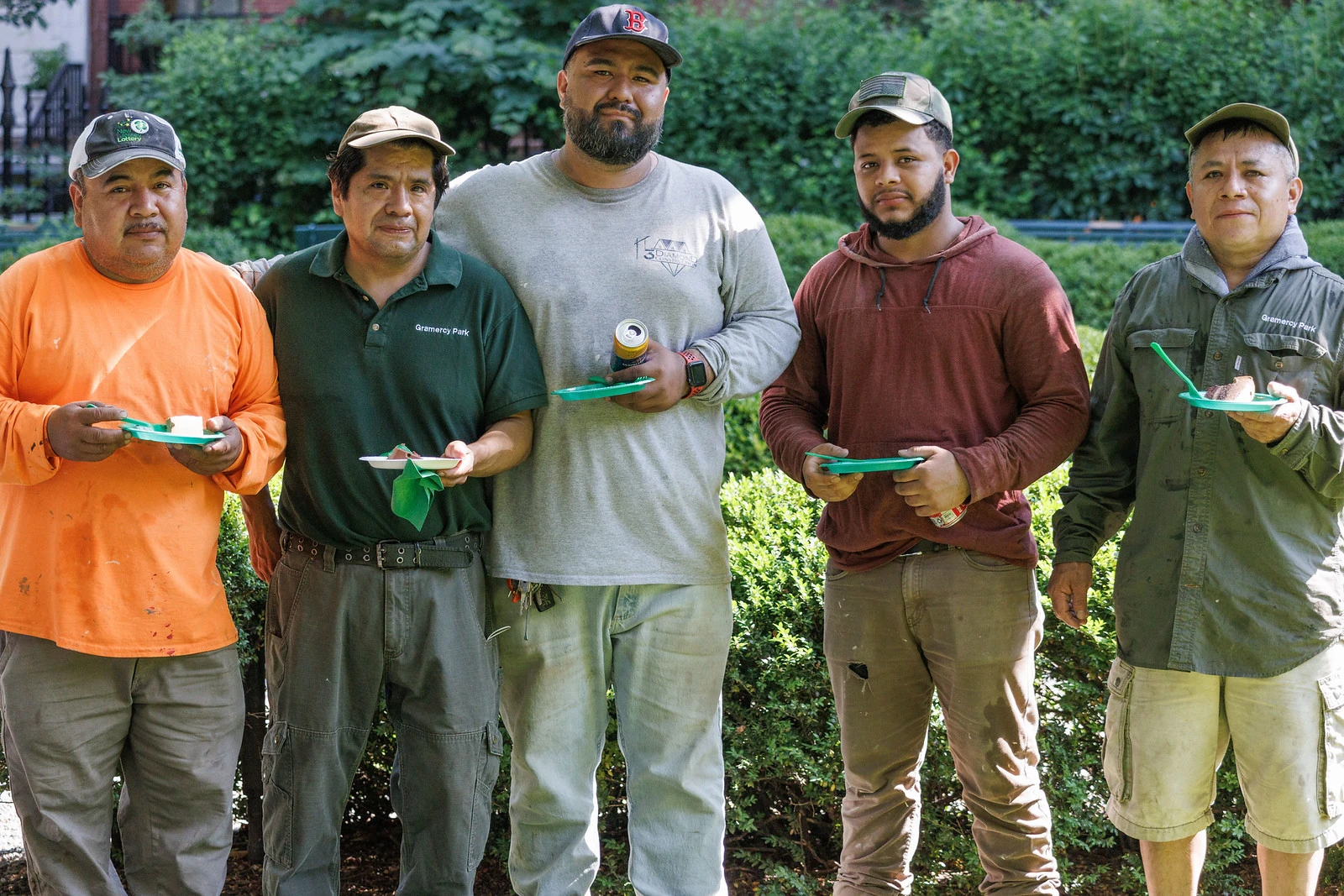 Amando and four friends stand together in Gramercy Park holding plates of birthday cake.