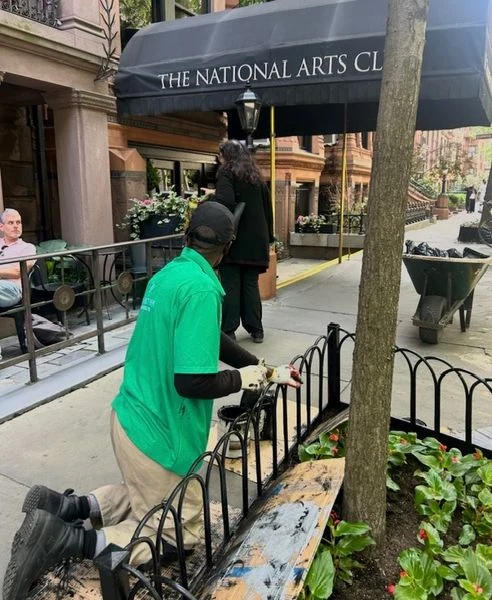 A Clean Streets worker paints a tree guard outside the National Arts Club.