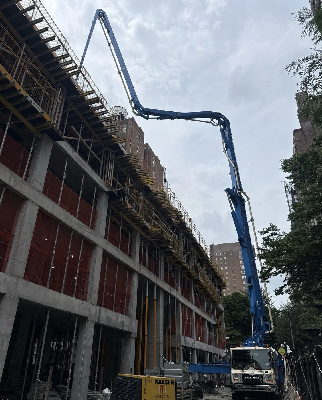 A concrete-pump truck extends its boom alongside the unfinished building.