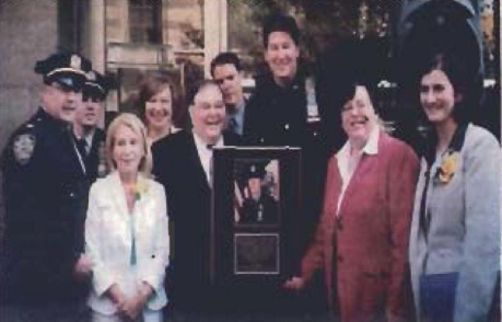 A group stands together at an awards presentation, with one person holding a framed plaque.