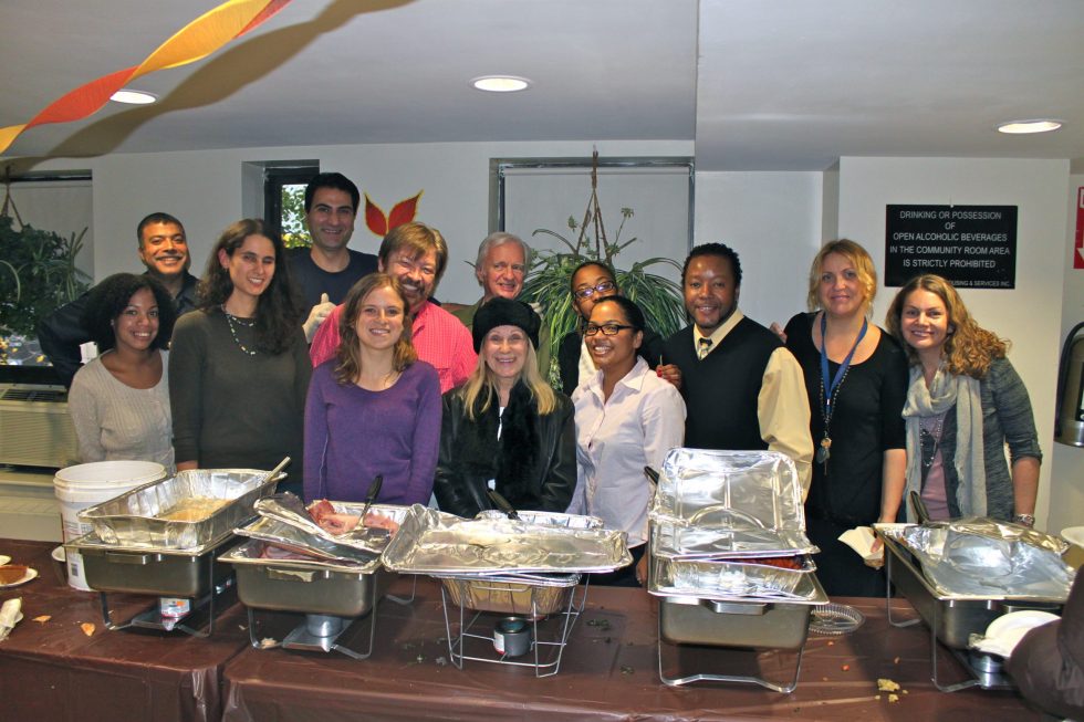 A group of volunteers poses behind buffet trays in a dining room.