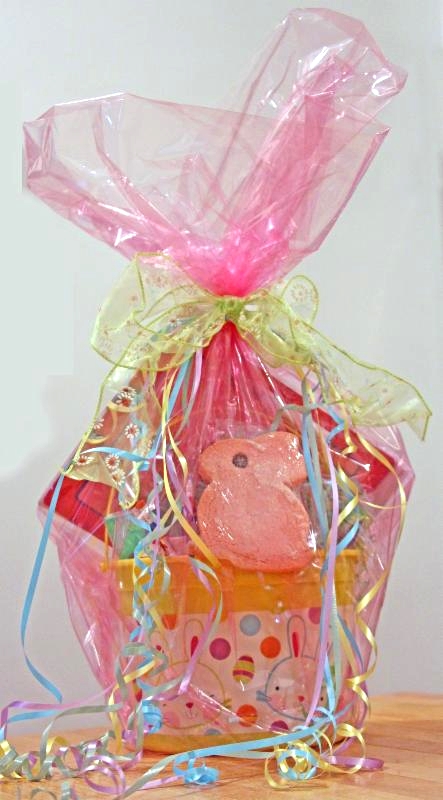 A gift basket wrapped in pink cellophane with toys and Easter treats.