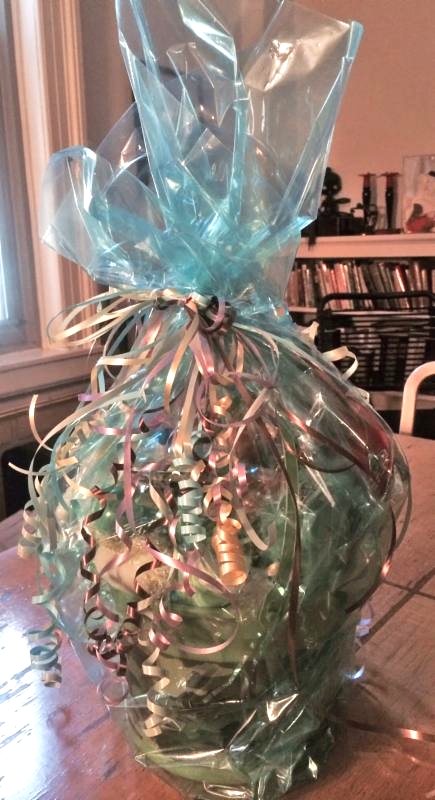 A gift basket wrapped in blue cellophane with toys and Easter treats.