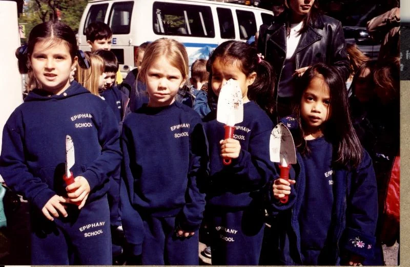 Schoolchildren hold small plants for a neighborhood memorial garden.