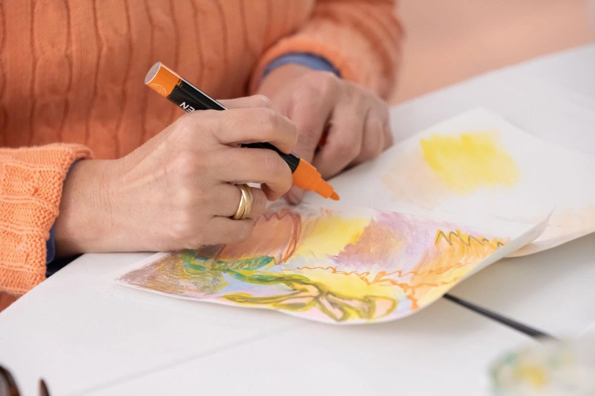A person draws with pastels at an art activity.