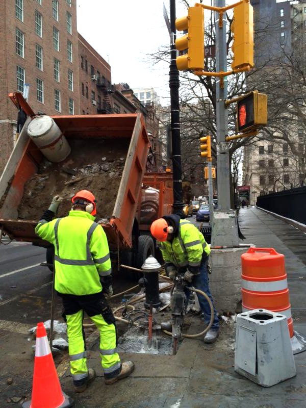 Workers and utility equipment at Gramercy Park South and Irving Place beside the Park fence.