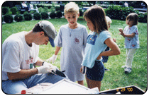 A Health Department worker speaks with children beside surveillance equipment in the Park.